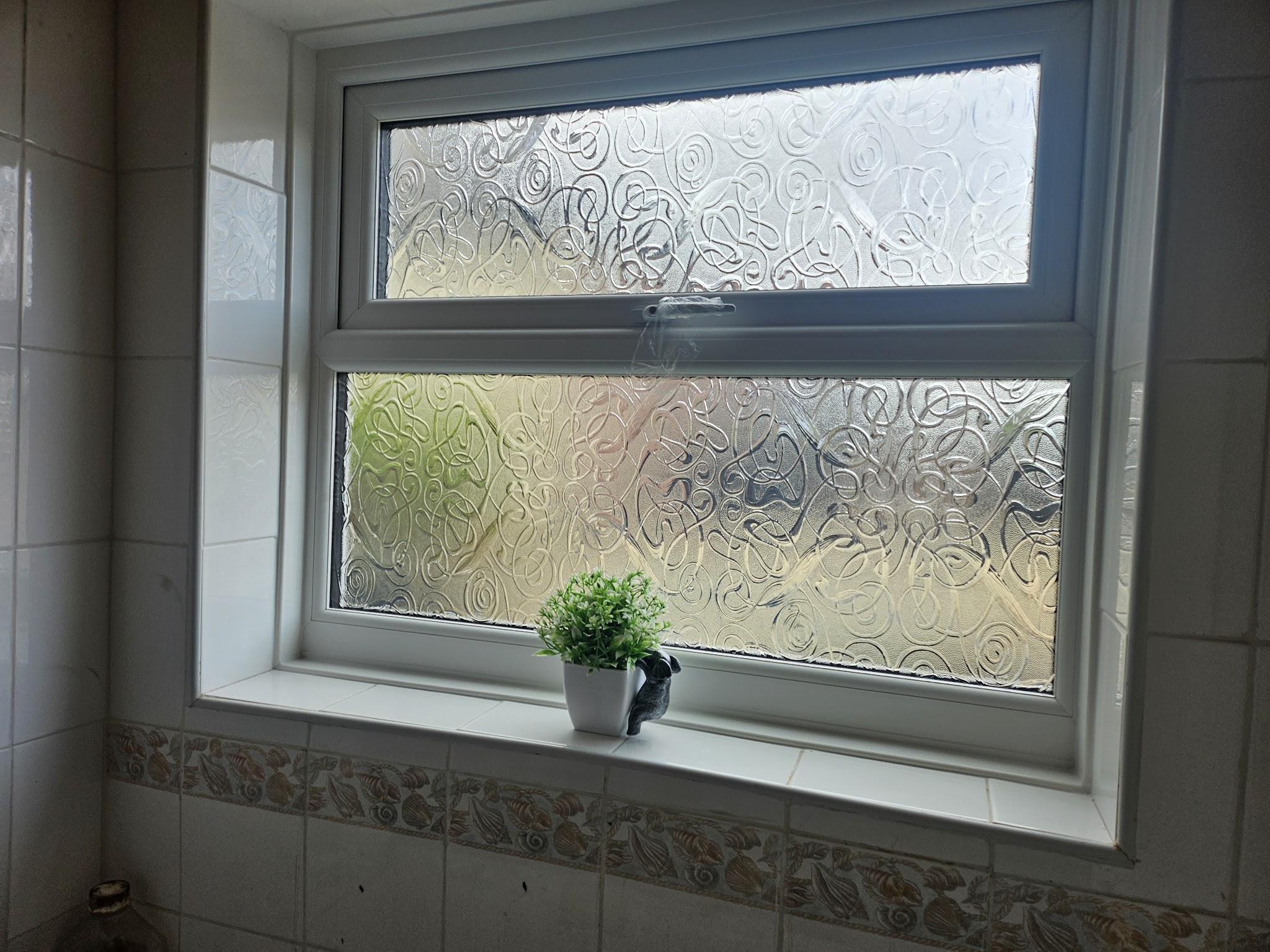 New white window with obscure glass in a tiled bathroom