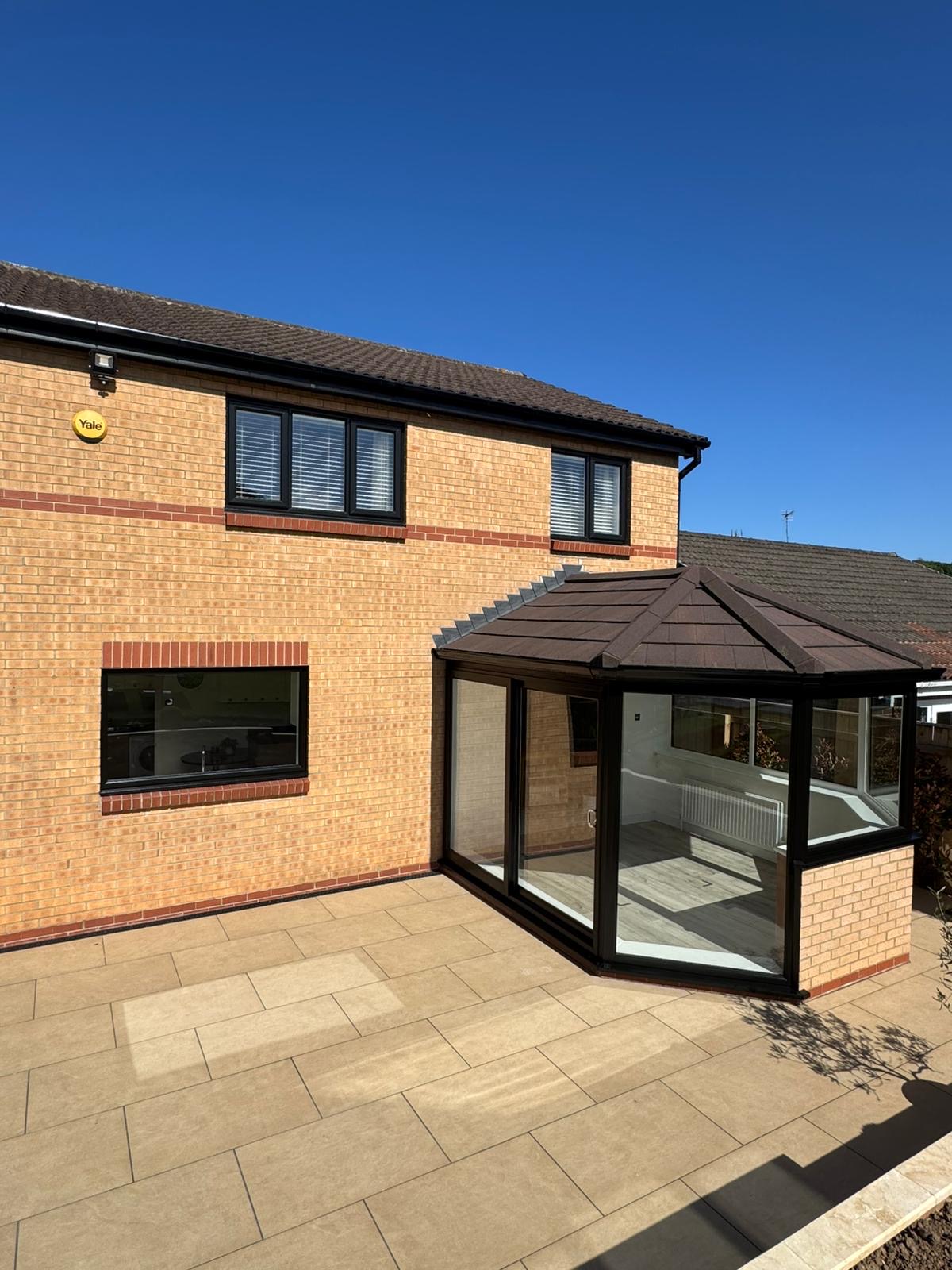 Conservatory with a dark tiled roof on a sandstone patio