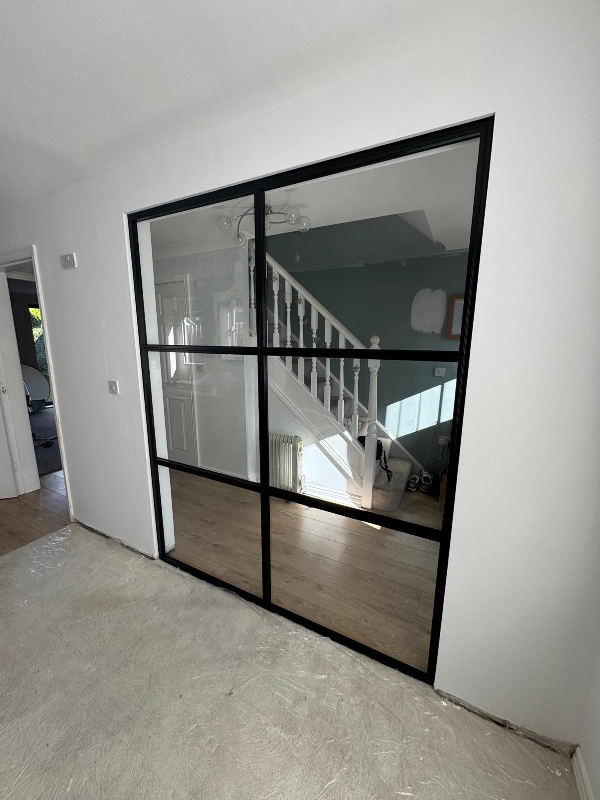 Internal black-framed glass screen with glazing bars beside a staircase